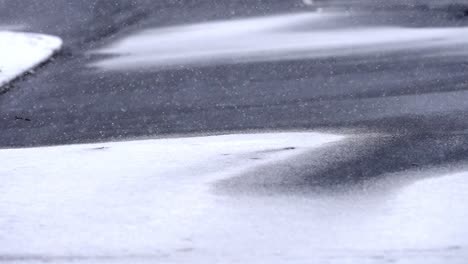 light snowfall on snow covered asphalt, street, road, static shot of snowflakes falling in winter, copy space, background footage