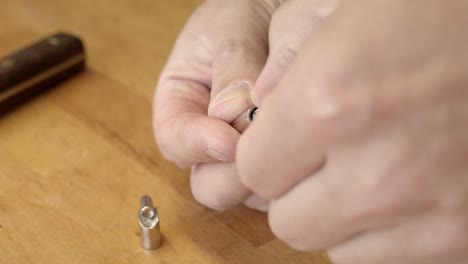 artesano agregando un broche de pulsera en una banda de color plateado, vista de cerca