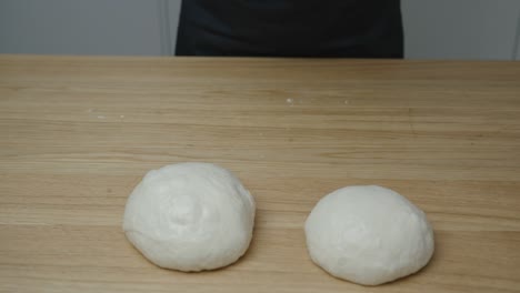 hombre formando pequeñas bolas de masa para pizza con sus manos