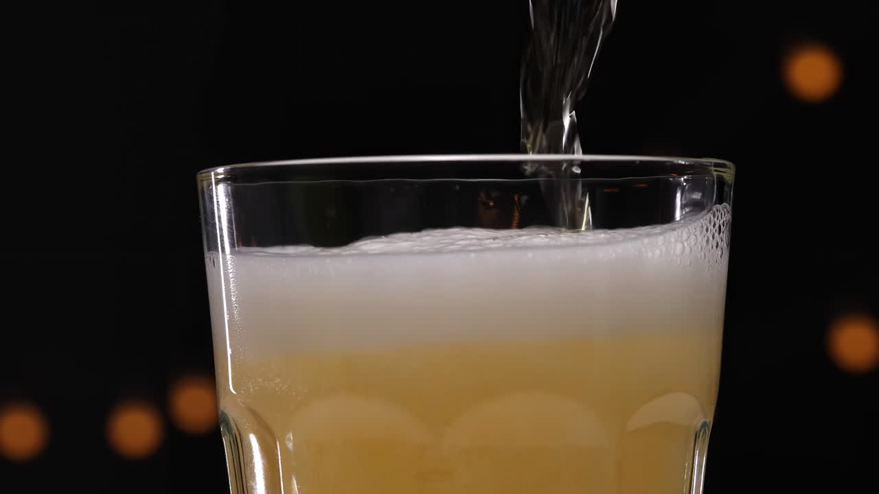 Rahat bir pub ortamında, camın kenarından taşan kalın, köpüklü, beyaz bir başlık oluşturan, yeni doldurulmuş bir pint altın rengi bira. Reklamlar ve serinletici bir içecek için mükemmel.