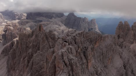 aerial orbit shot around cross on peak of tre cime di lavaredo mountains in dolomites with dark cloudscape on top, south tyrol