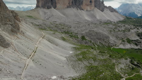 slow drone reveal shot of tre cime di lavaredo in dolomites, italy on a cloudy day