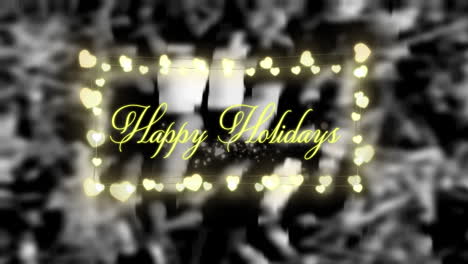 decorative heart shaped fairy lights and happy holidays text against black background