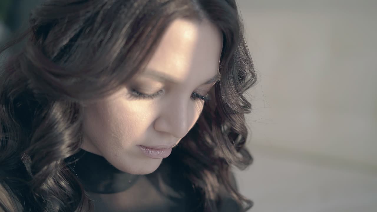 어두운 머리카락의 소녀가 밝은 배경에서 포즈를 취합니다.