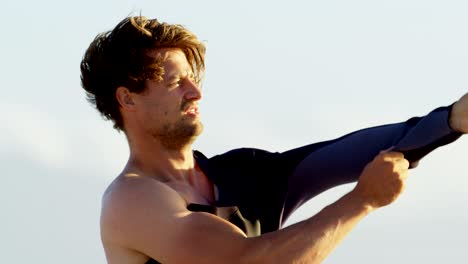 surfista masculino con traje de neopreno en la playa 4k