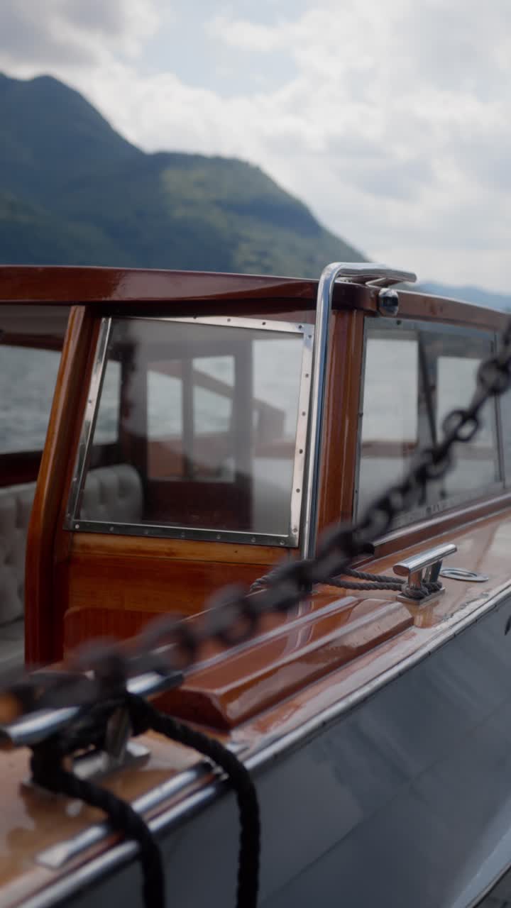 Vertical close-up of wooden speedboat shimmering with water reflections at dock, Lake Como, Italy (Lago di Como, Italia)