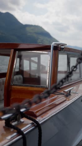 vertical close-up of wooden speedboat shimmering with water reflections at dock, lake como, italy (lago di como, italia)