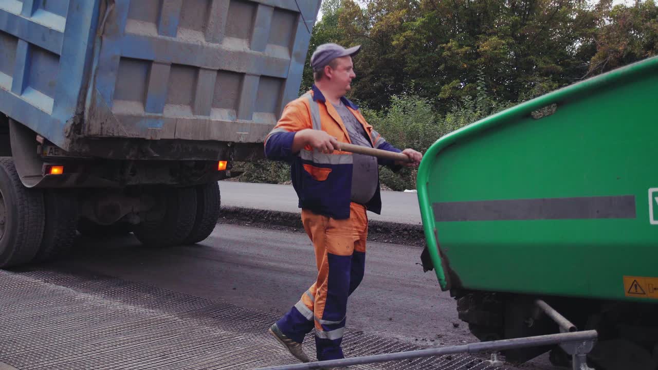 VINNYTSIA, UKRAINE - SEPTEMBER 10, 2018: the truck pours out the asphalt into Asphalt paver
