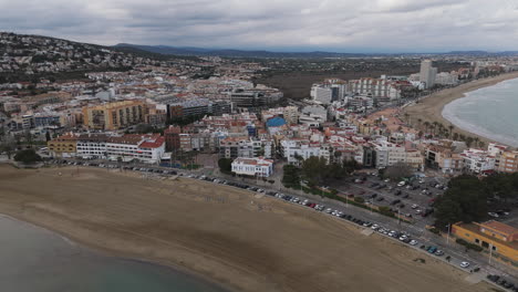 drone captures long beach stretch beside peniscola old town and gentle rolling waves