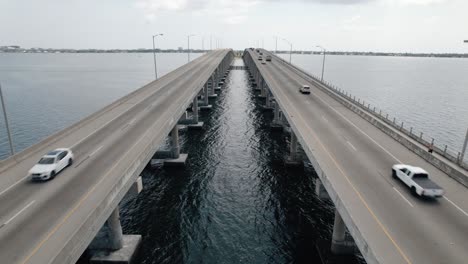 locked down aerial shot of traffic driving over a coastal bridge in florida