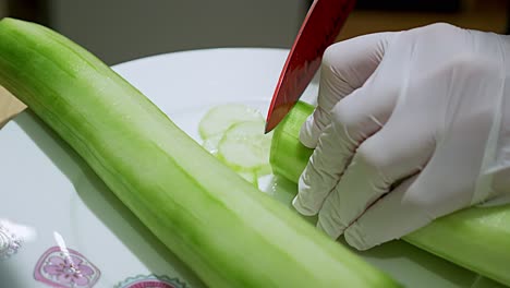 un pepino verde pelado que se corta en rodajas con uno entero al lado