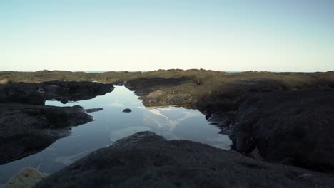 Small-tide-pool-encased-in-lava-rock-on-a-clear-blue-sky-day