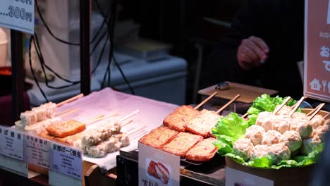 person cooking skewers at a street food stall