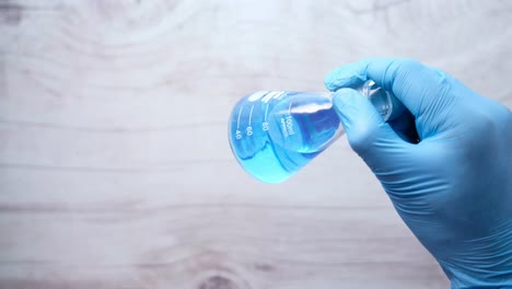 scientist holding a conical flask with blue liquid