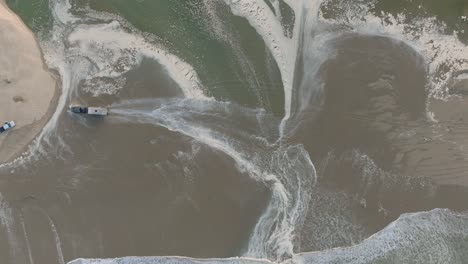 Aerial-Top-Down-Drone-shot-of-Truck-Driving-on-Pismo-Beach-California-Through-Water-at-Sunrise