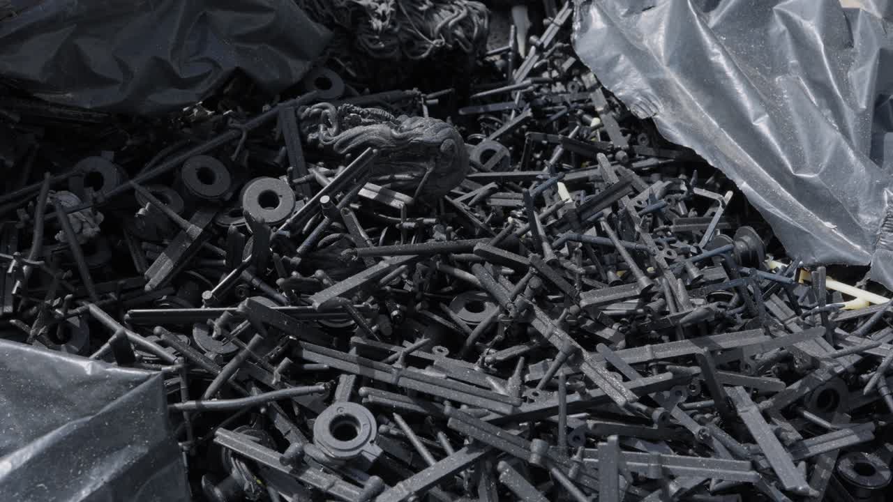 Massa di piccoli scarti industriali di plastica nera e parti stampate in un'area di raccolta.