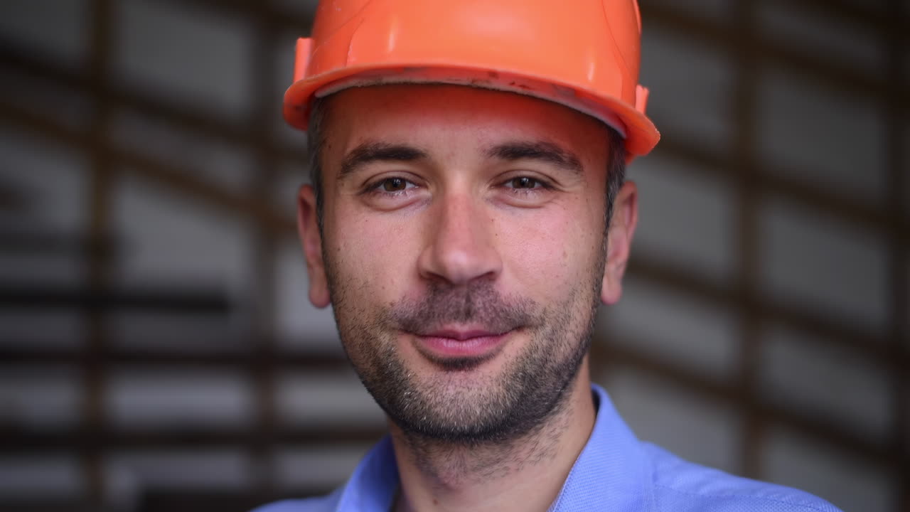 A site manager wearing an orange safety helmet smiling on a construction site