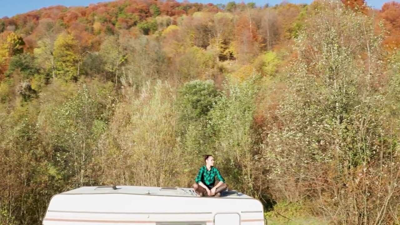 Donna ammira il paesaggio montano dal tetto di un camper