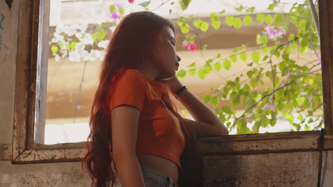 A woman posing in front of a window with bougainvillea