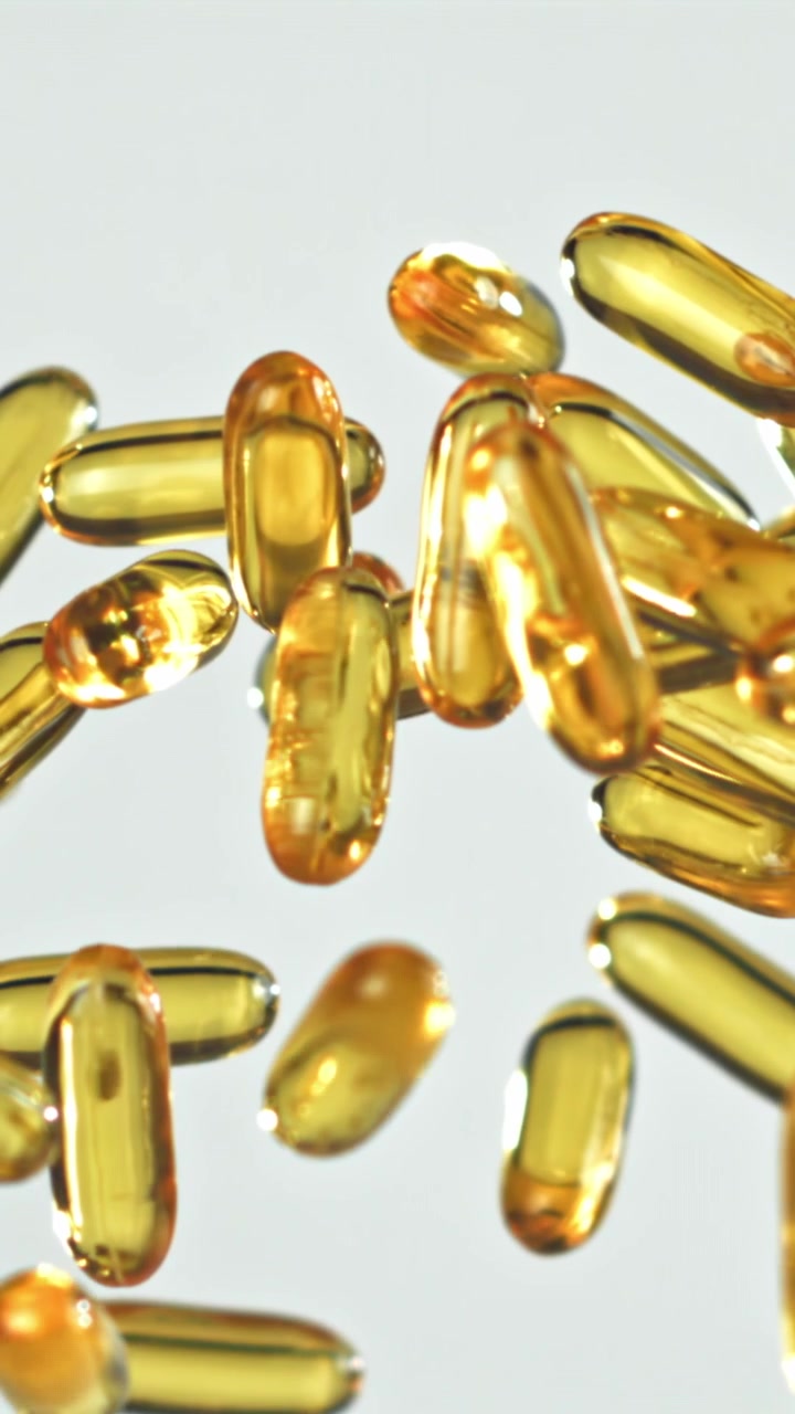 Capsule softgel dorate che cadono e rimbalzano al rallentatore