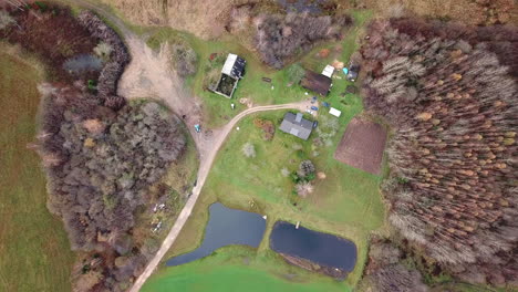 aerial descending shot footage of old houses in rural countryside village with two ponds next to it