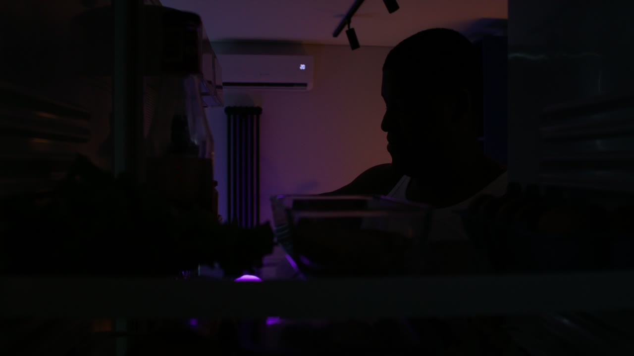 Person eating and drinking from fridge at night