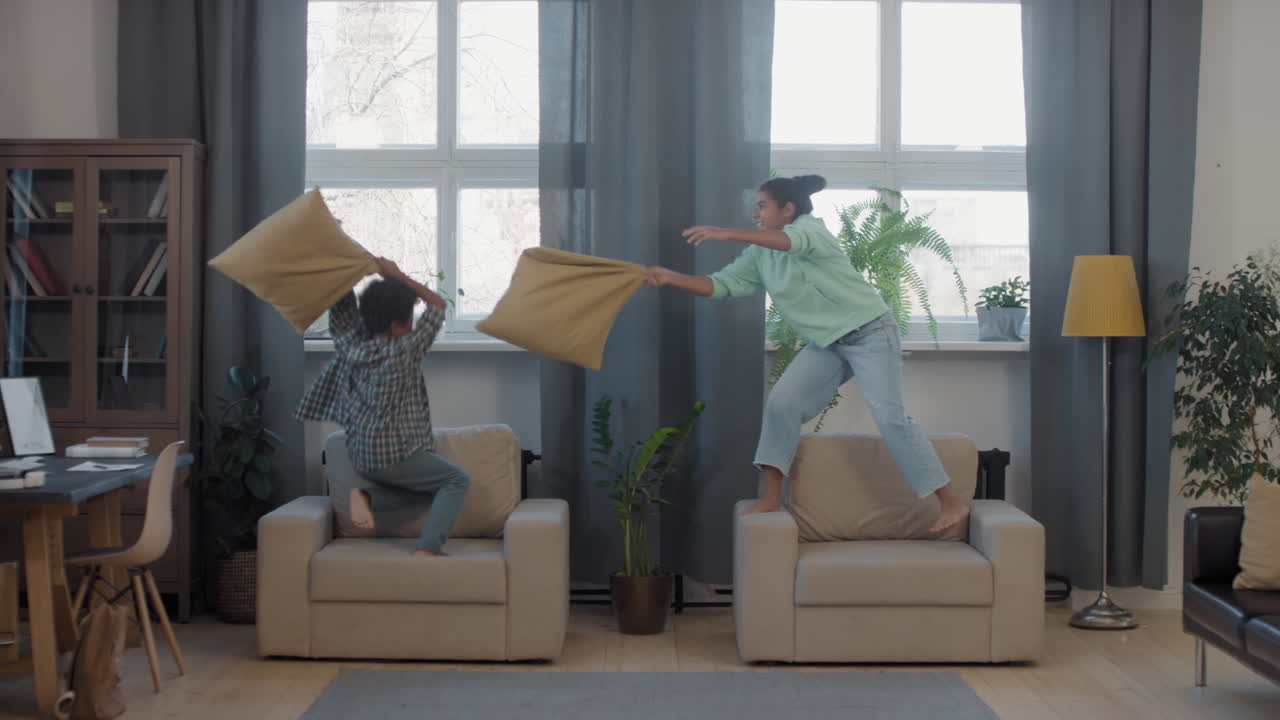 Mixed-Race Siblings Pillow-Fighting In Living Room