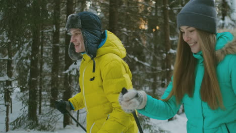 portrait of a married couple. a man in a yellow jacket and a woman in a blue jumpsuit in the winter in the woods skiing in slow motion