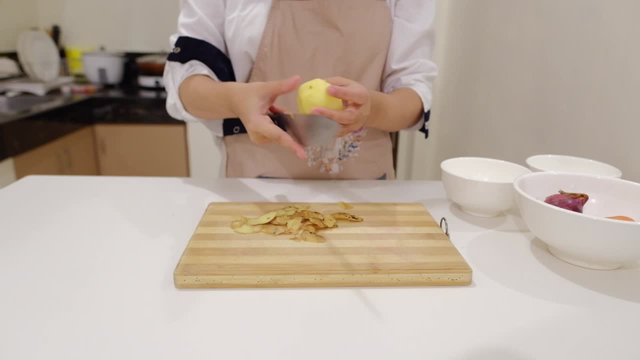 mujer con delantal está pelando patata en la cocina