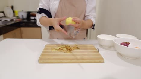Woman-With-Apron-Is-Peeling-Potato-In-The-Kitchen