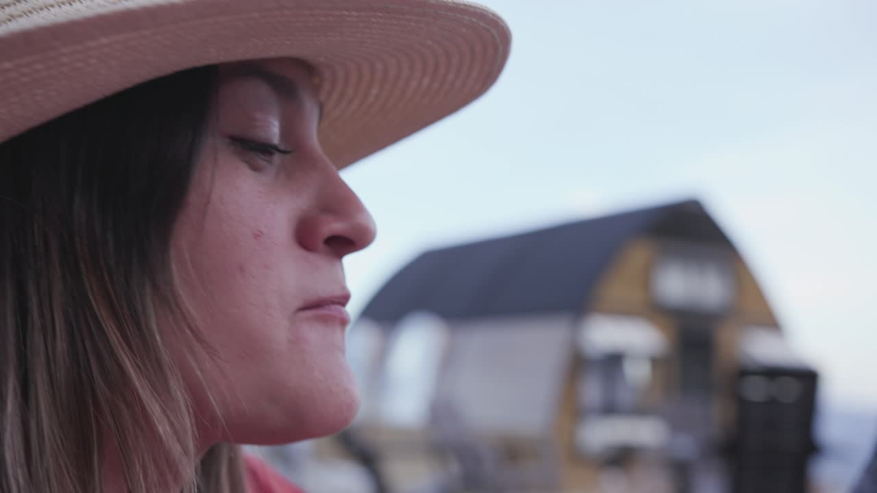 mujer con sombrero come fresa con chocolate y mira al cielo