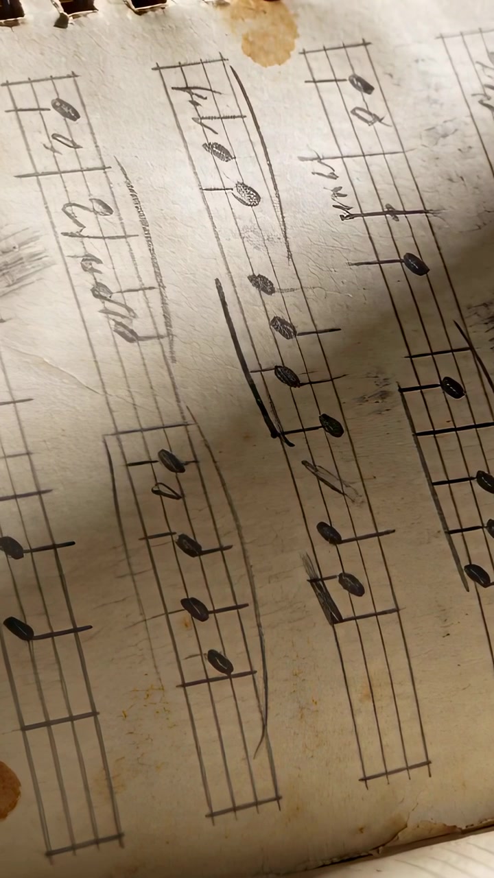 Vertical video: Panning handheld camera slowly over spiral music notebook on desk, centering mark