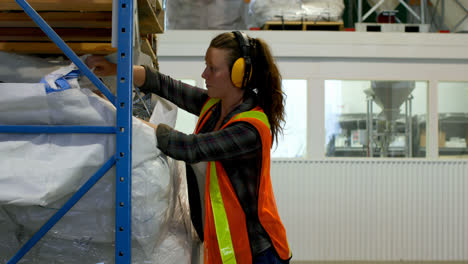 side view of young caucasian female worker checking stock in factory 4k