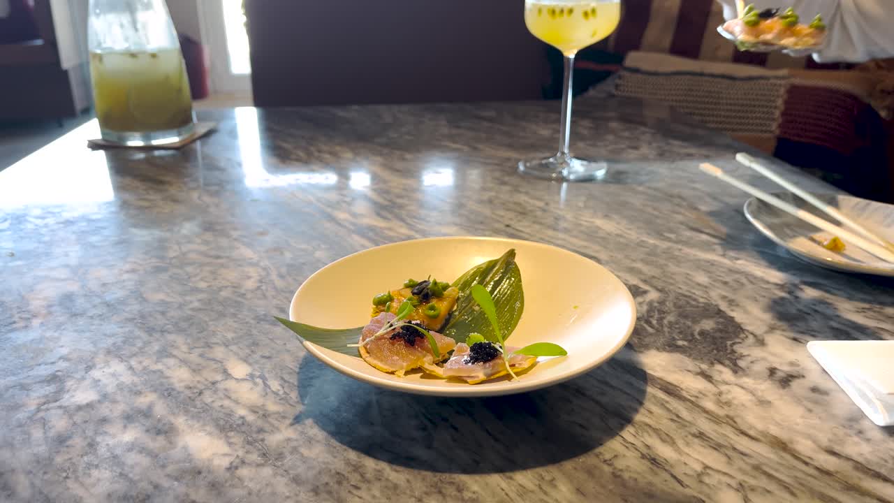 한 사람이 조심스럽게 접시에서 미세하게 인 맛있는 음식의 일부를 가져와 섬세한 프레젠테이션을 보여줍니다. 접시에는 활기찬 장식과 예술적 요소가 있습니다.