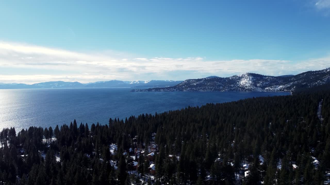 Aerial drone shot, flying over the woods towards the crystal clear lake in Lake Tahoe, Nevada-California