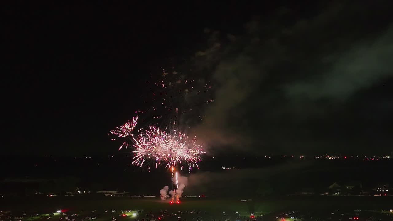 A vibrant fireworks show illuminates the night sky above the city, captivating spectators gathered below.