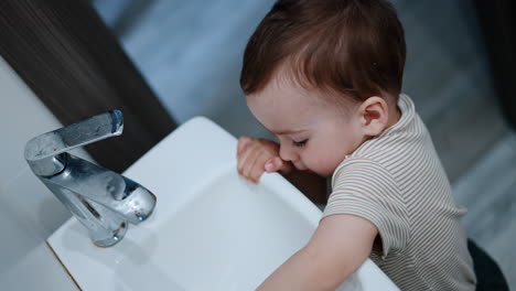 excited happy caucasian boy carefully opens the water. little child plays with water. top view close up.