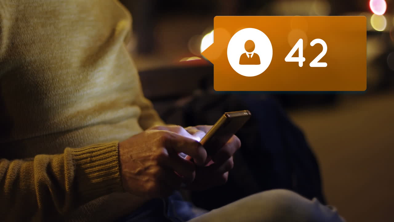 hombre sentado en un banco por la noche mientras escribe en su teléfono 4k