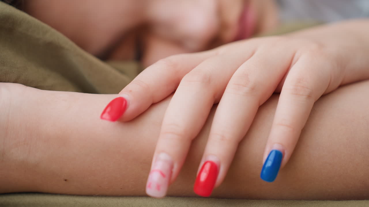 Calm Student Shows Painted Nails, Relaxed Individual Displays Bright Nail Polish In Dorm Setting, Serene Student Lounges In Dorm With Multicolored Nails During Quiet Afternoon Moment