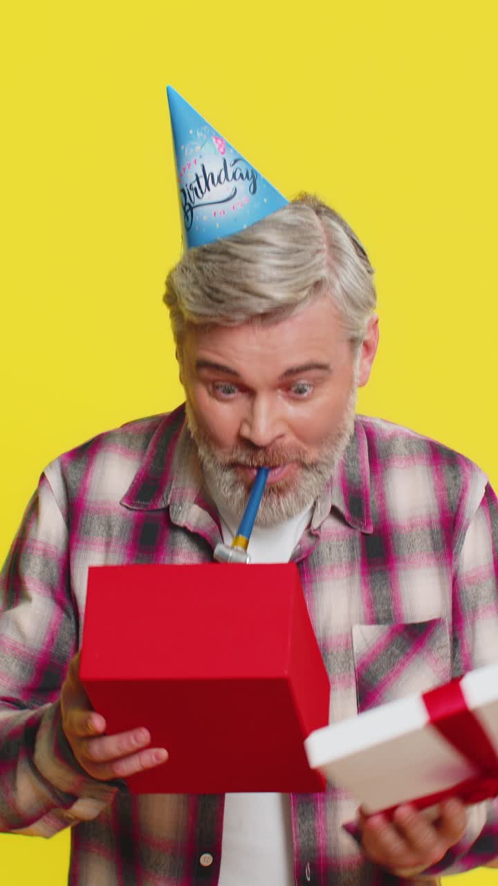 Happy mature man surprise gift moment party cone hat joyful shock red bow birthday excitement