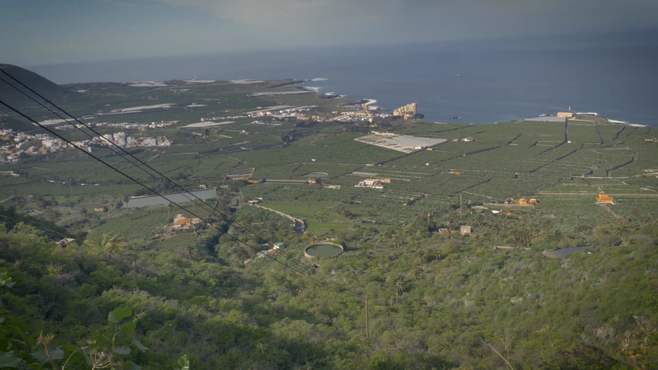 아래의 농장과 마을이 내려다보이는 무성한 녹색 언덕의 높은 곳에서 테네리페 해안의 전망