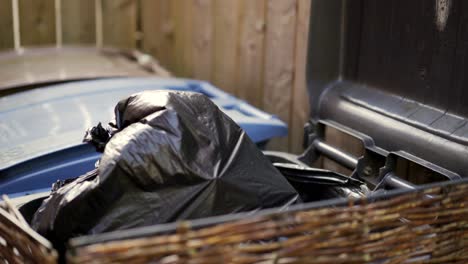 putting a black bag of trash in the trash can