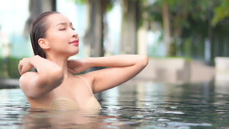 Close-up-an-attractive-woman-in-a-swimming-pool-pushes-her-wet-hair-away-from-her-face