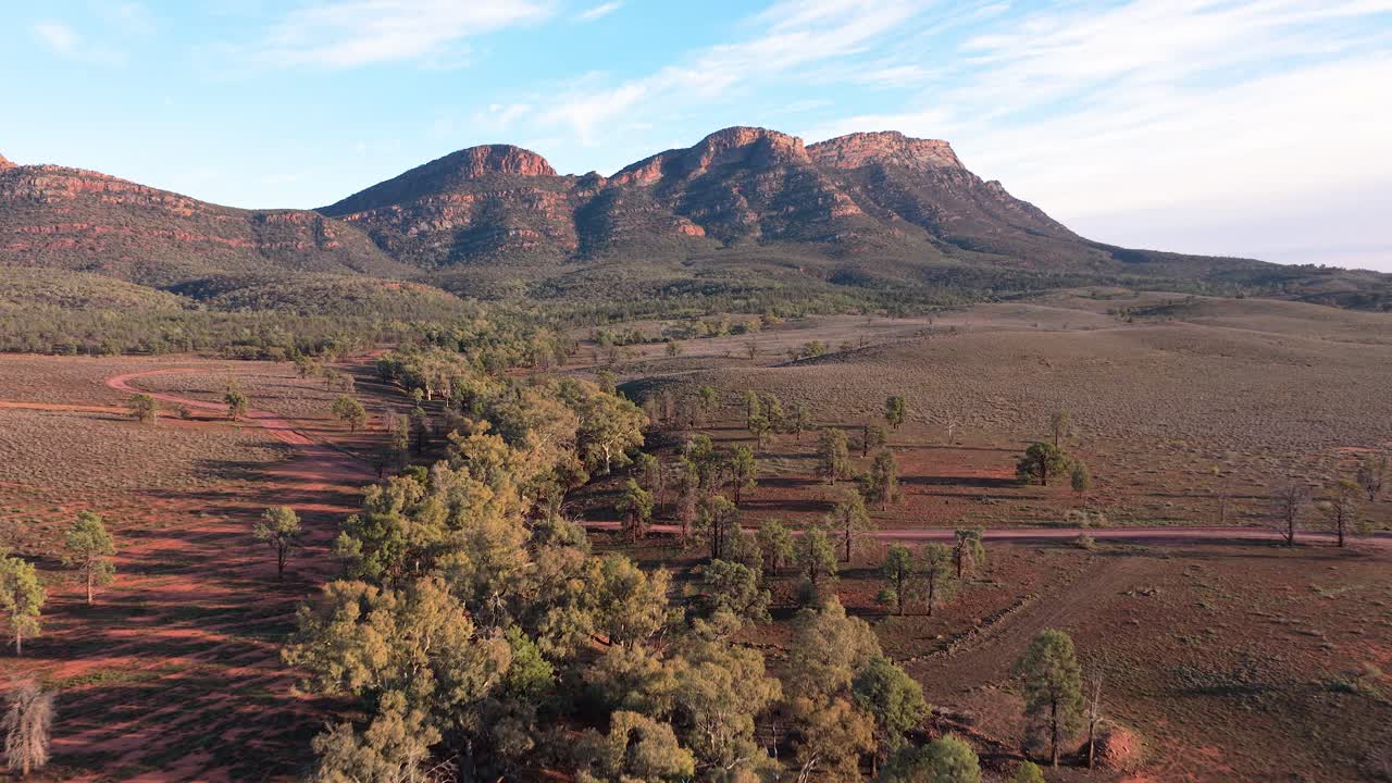 Drone pulls back to reveal wide Flinders Ranges cliffs, valleys and vast outback scenery, South Australia