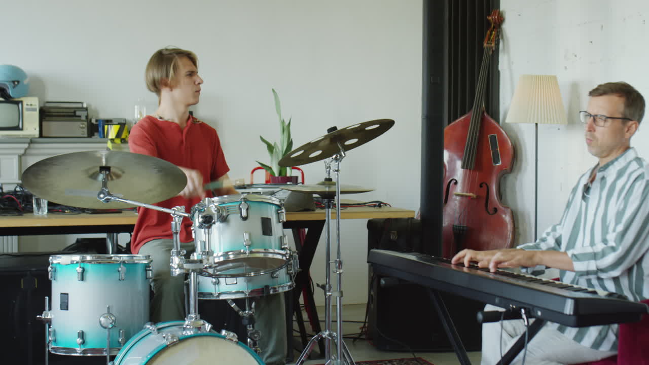 Two musicians playing drums and keyboard in a studio