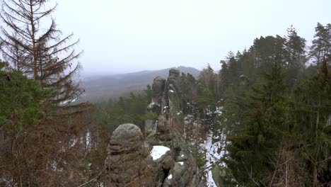 outlook on a sandstone rock formation in prachov rocks, bohemian paradise, in winter with flying snowflakes, truck right