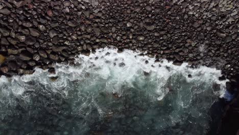 ocean waves gently crashing into pebbles beach, view from above, tilt down