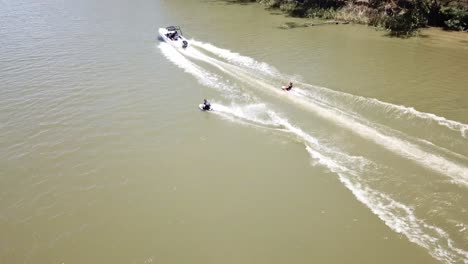 Drohnenantenne-Bewegt-Sich-Mit-Schnellboot-Und-Wasserski-über-Den-Fluss