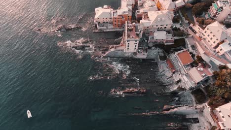 beautiful aerial morning scenery at the coast of genoa in liguria, italy on a misty sunrise - panning up shot