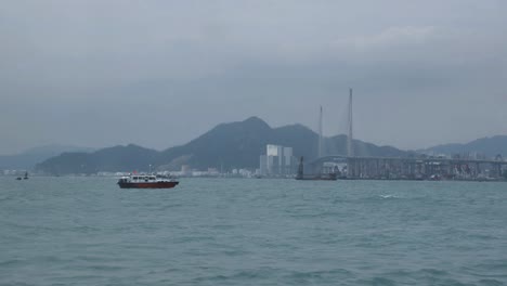 view from over the water of small boat and hong kong hills